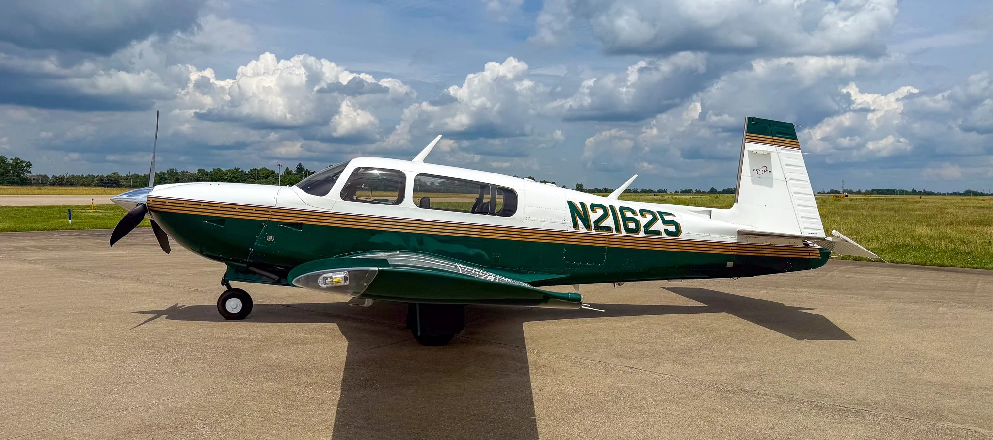 A side view of the white and green Mooney M20 aircraft with registration N21625 on an airfield.