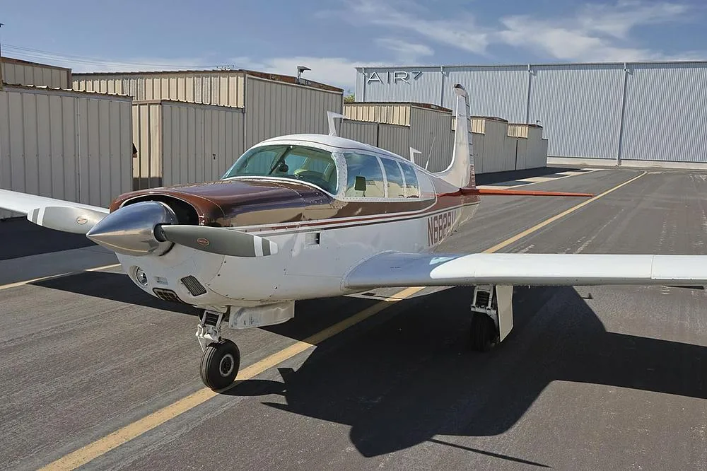 A front-quarter view of the brown and white single-engine aircraft, N6829V, parked on an airfield.