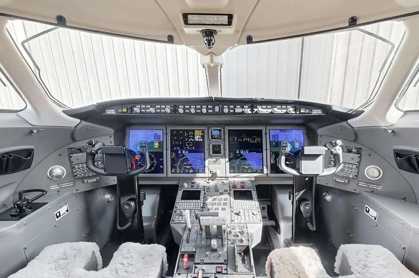 The modern glass cockpit of a business jet with multiple digital displays and controls.