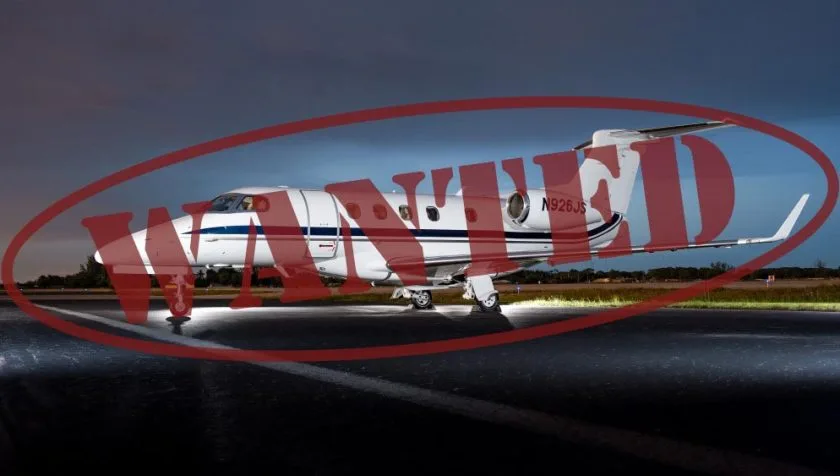 A white business jet with blue stripes, registration N926JS, is parked on a tarmac at night with ground lighting.