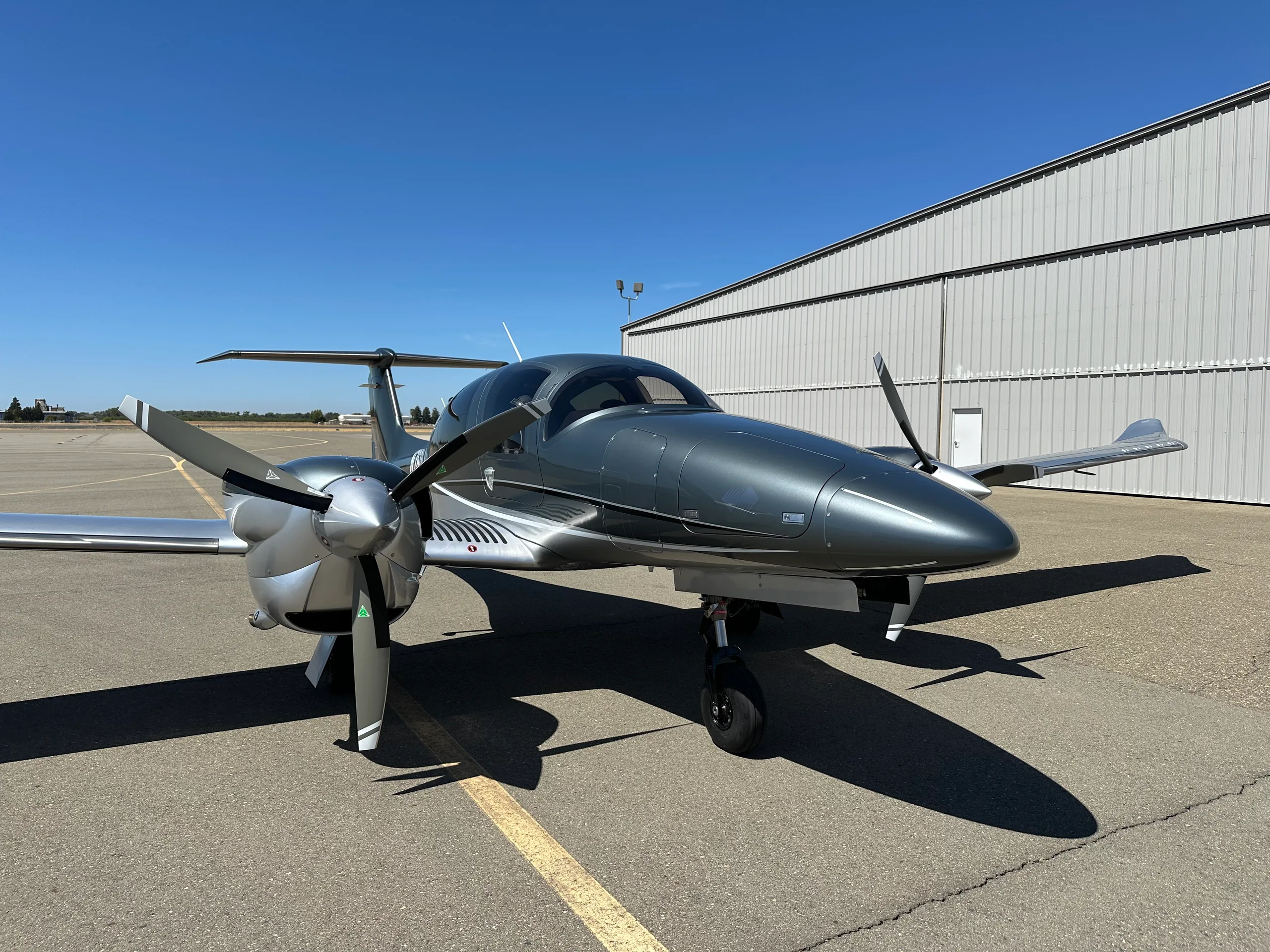 A front view of a grey and silver Diamond DA62 aircraft with registration N769LA parked on an airfield.