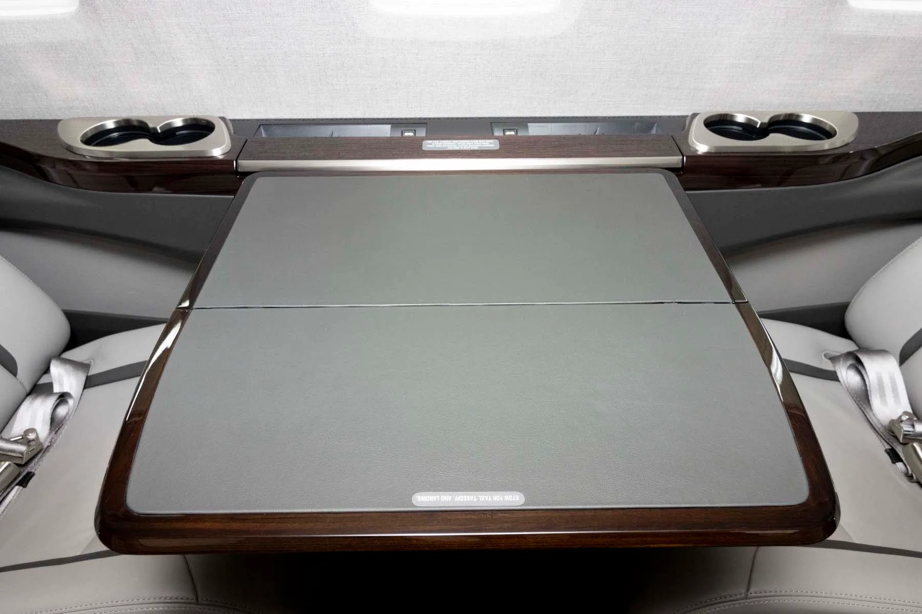 A grey leather table extended from the side panel in the private jet's cabin.