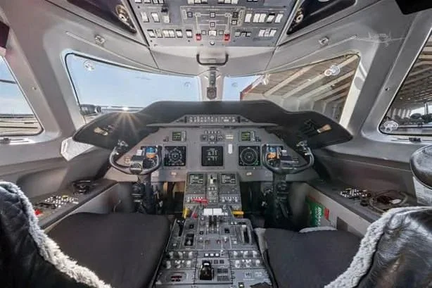 The spacious cockpit of a private jet, featuring a modern instrument panel with multiple digital displays and control yokes.