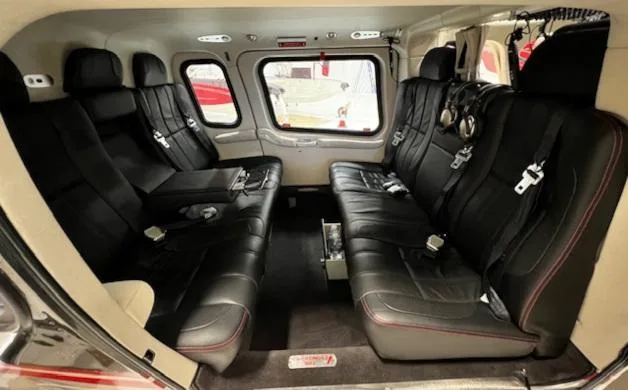 The luxurious black leather interior of a helicopter cabin, featuring two rows of passenger seating.