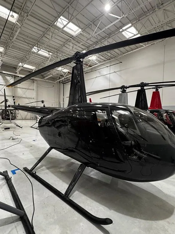 A black Robinson R-44 Raven I in a hangar.
