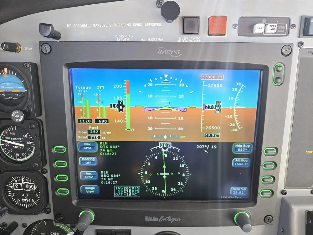A close-up of the Avidyne FlightMax Entegra primary flight display in the cockpit, showing flight data at 27,000 feet.