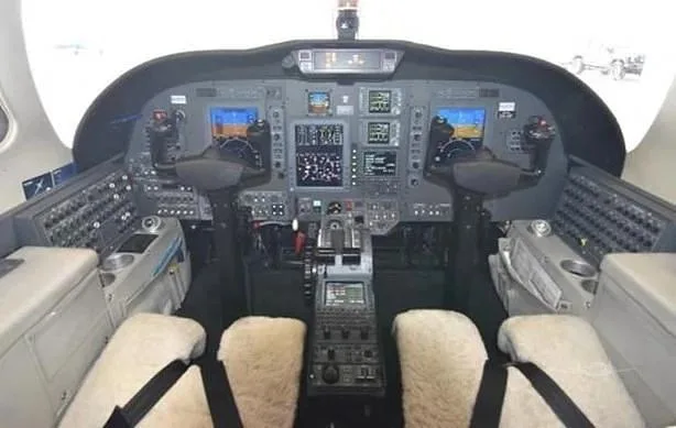 The modern glass cockpit of a business jet with multiple display screens and controls.
