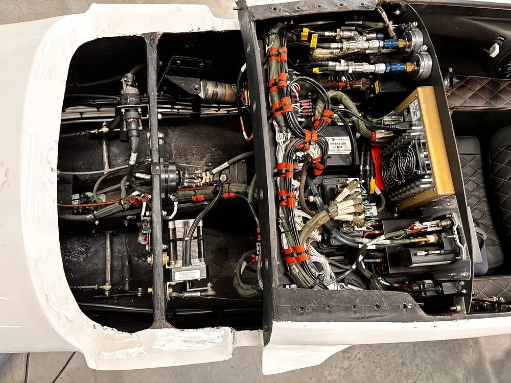 An open compartment of the aircraft reveals a complex network of wires, cables, and electronic components.