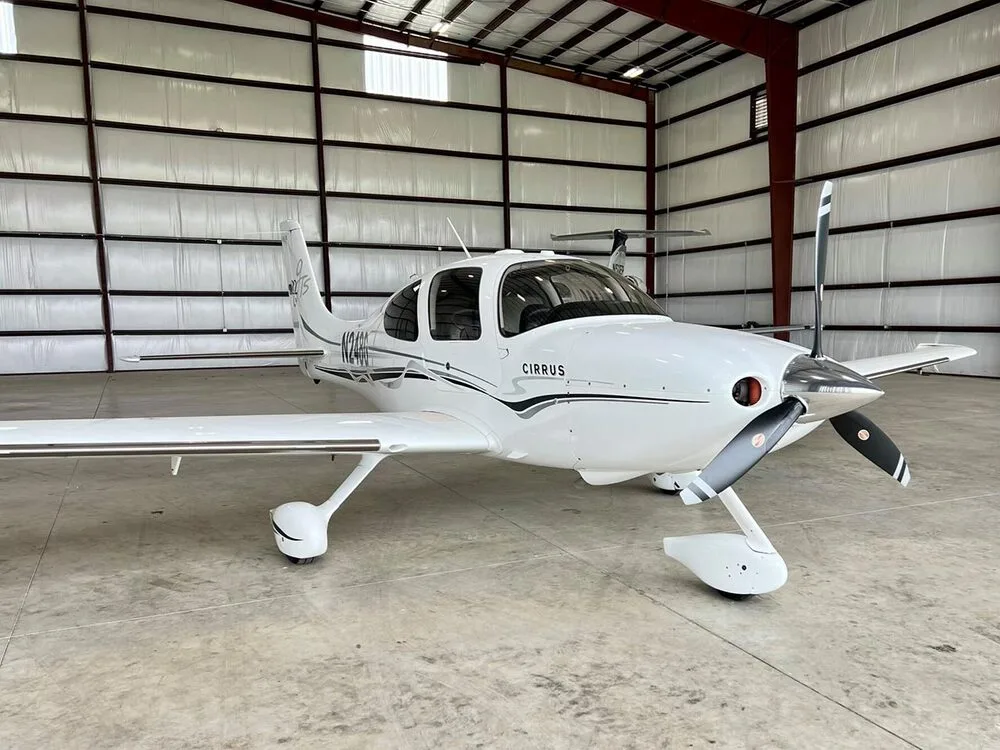 A three-quarter front view of a white Cirrus SR22 aircraft with registration N248G, parked in a hangar.