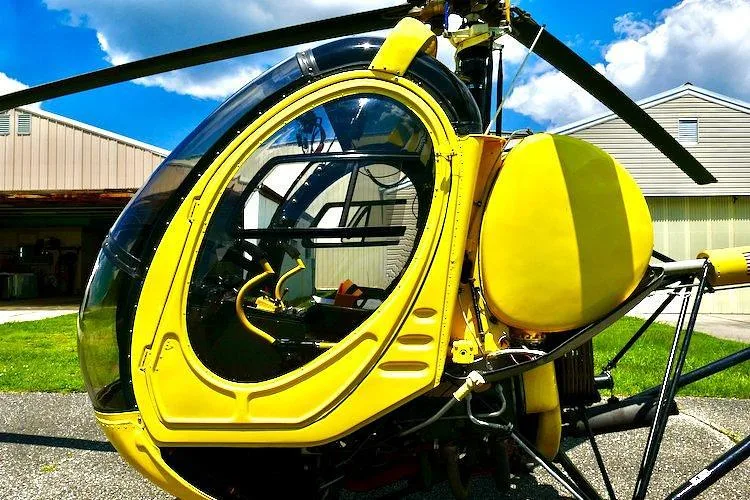 A close-up view of the front and side of a yellow single-engine helicopter, N8872F, showing its clear bubble canopy.