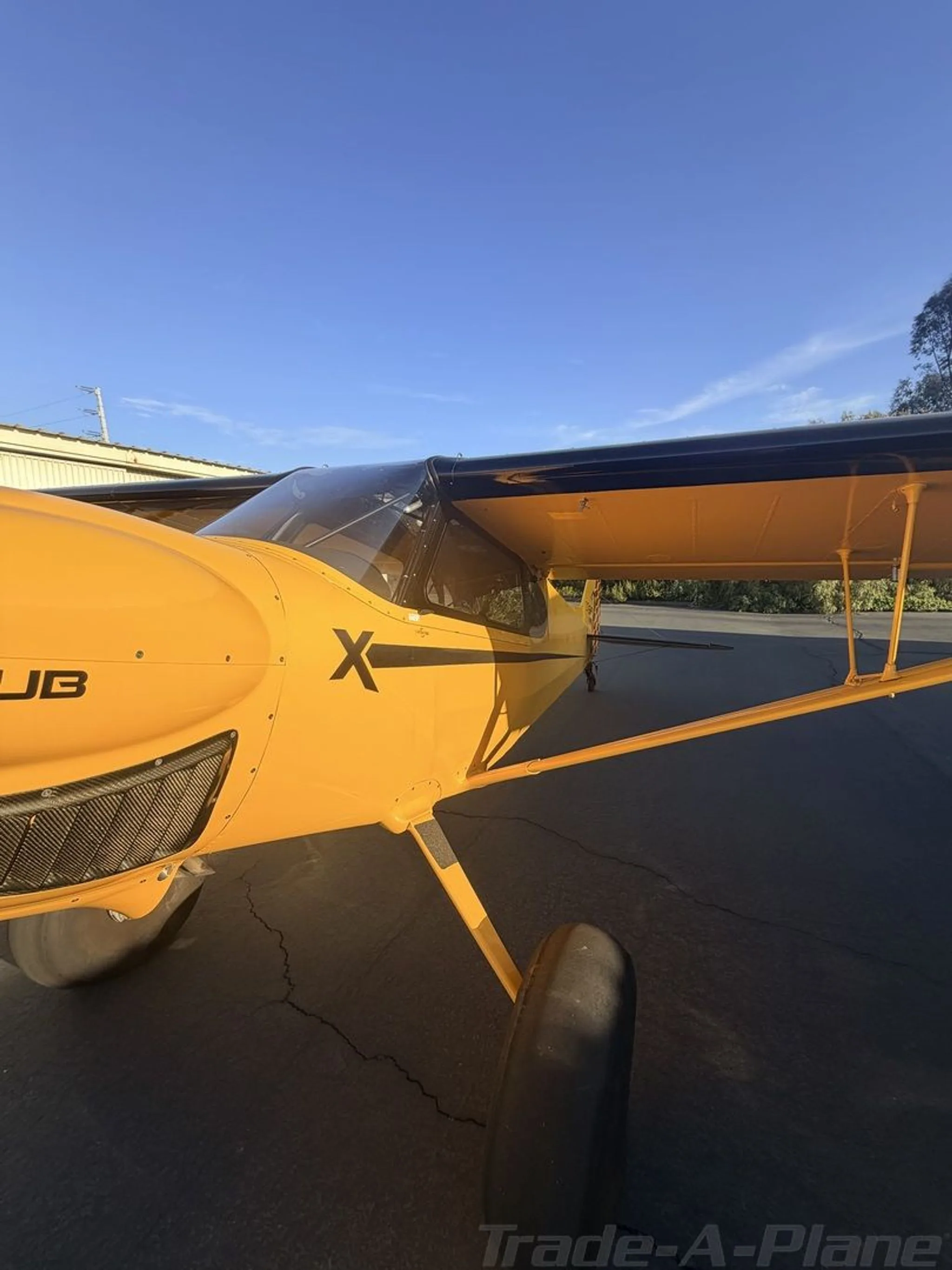 A close-up view of the front fuselage and propeller of a yellow CubCrafters XCub with black wings.