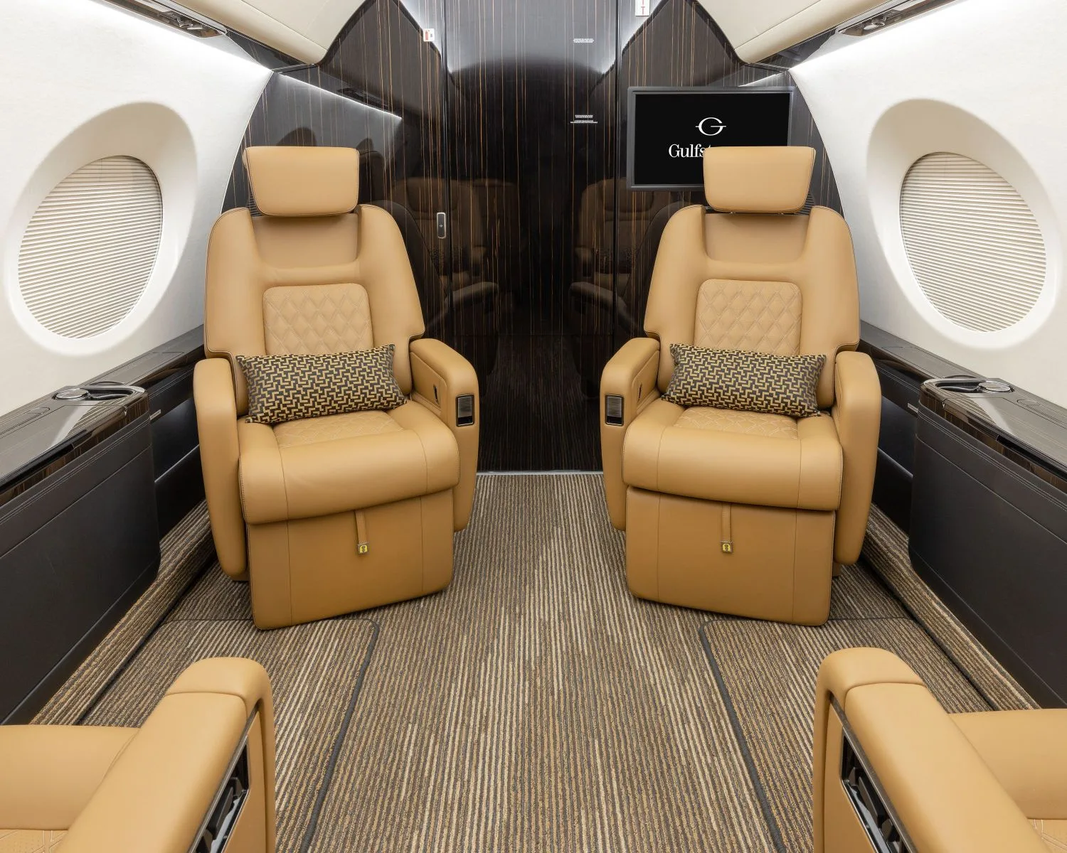 A view of the aircraft's interior with tan leather seats and a dark wood accent wall.