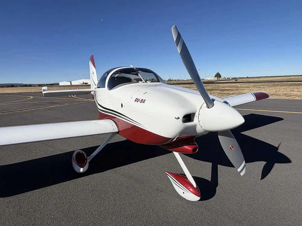A slightly different front-quarter view of the white and red Van's RV-9A aircraft N942R on an airfield.
