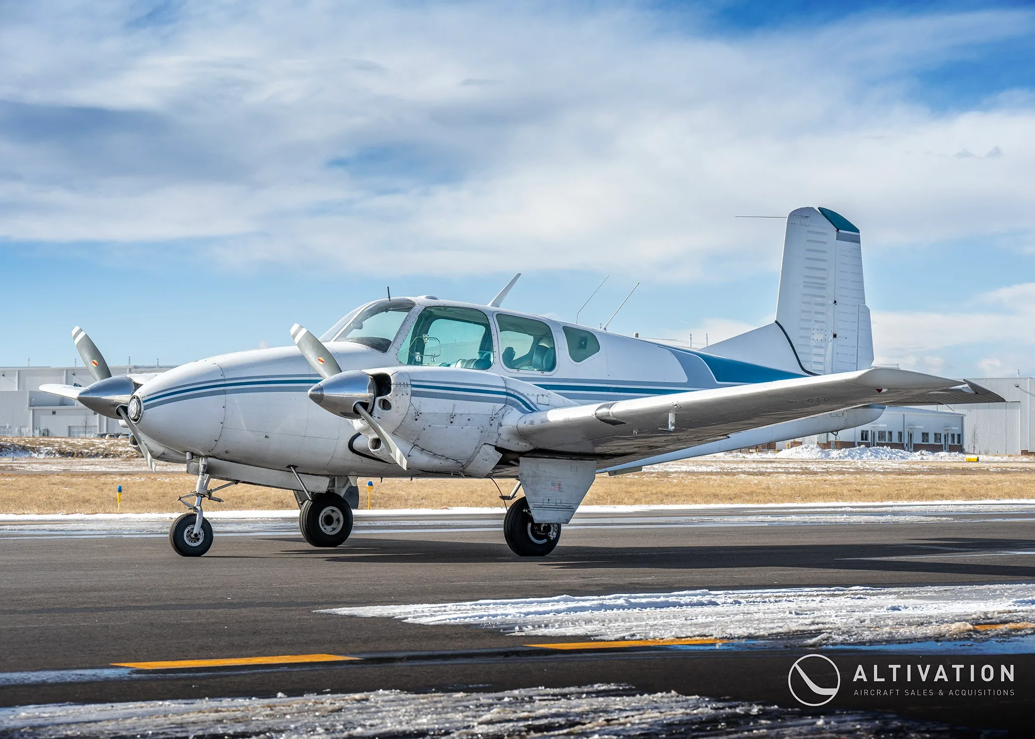 Side view of a white and blue twin-engine propeller aircraft on a tarmac.