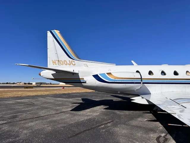 A close-up view of the tail section of the N700JC business jet, showing the blue and gold stripe livery and engine nacelle.