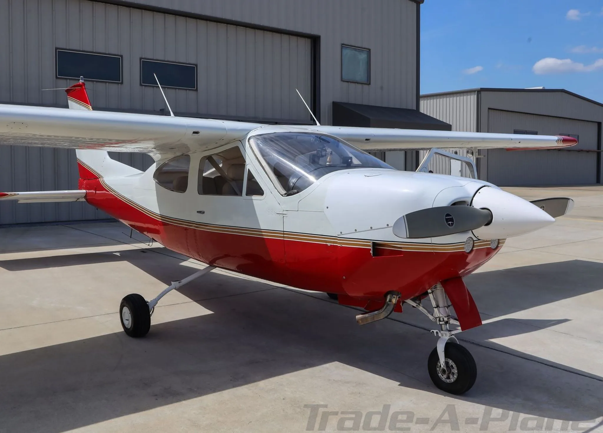A close-up view of the front of a red and white Cessna 177RG Cardinal with its propeller.