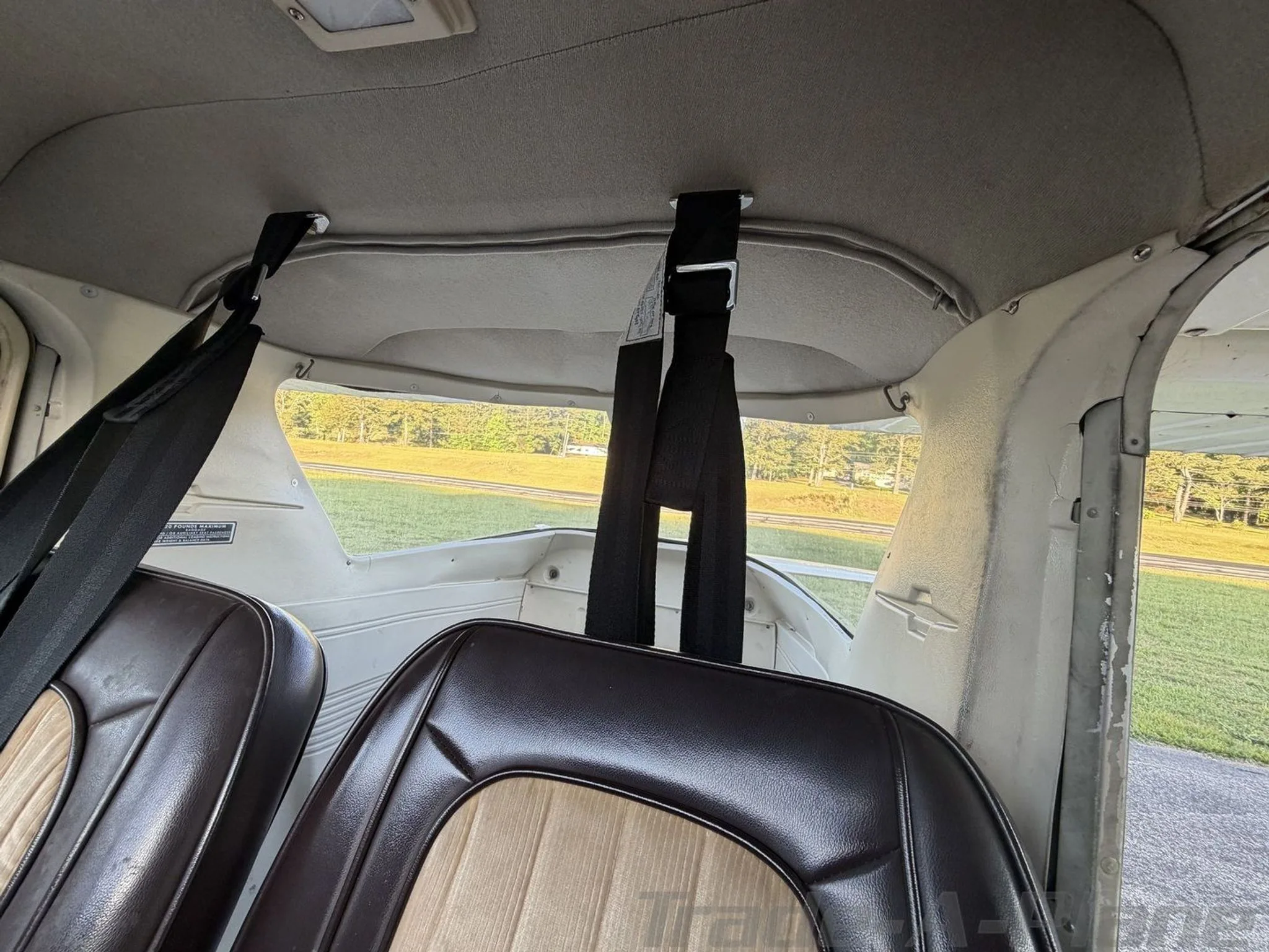 Interior view of the Cessna 172 rear cabin showing brown and tan upholstered seats and seatbelts.