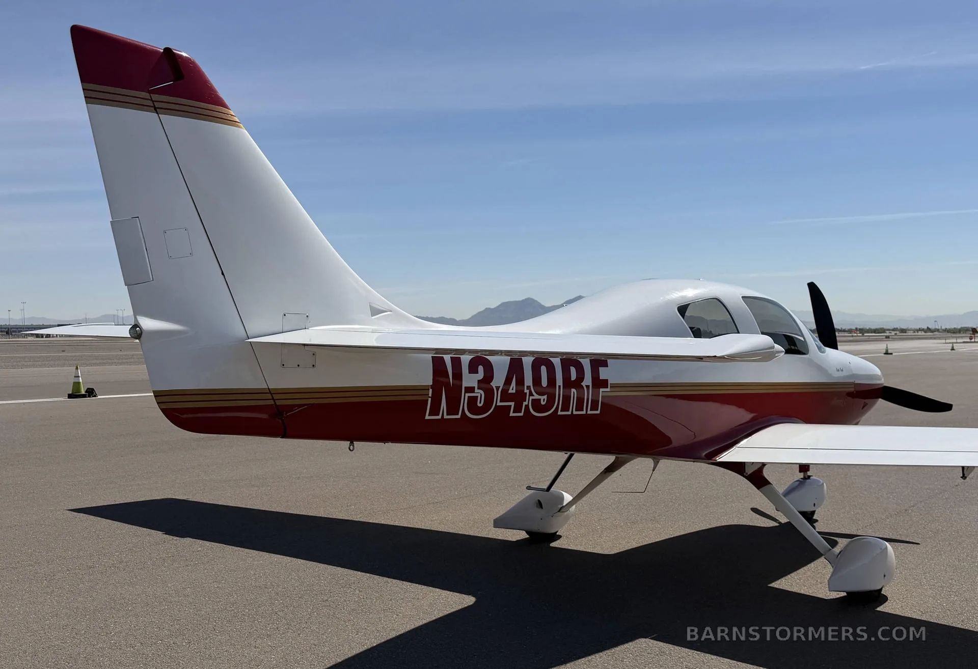 Rear view of a white and red single-engine aircraft, N349RF, on an airfield.