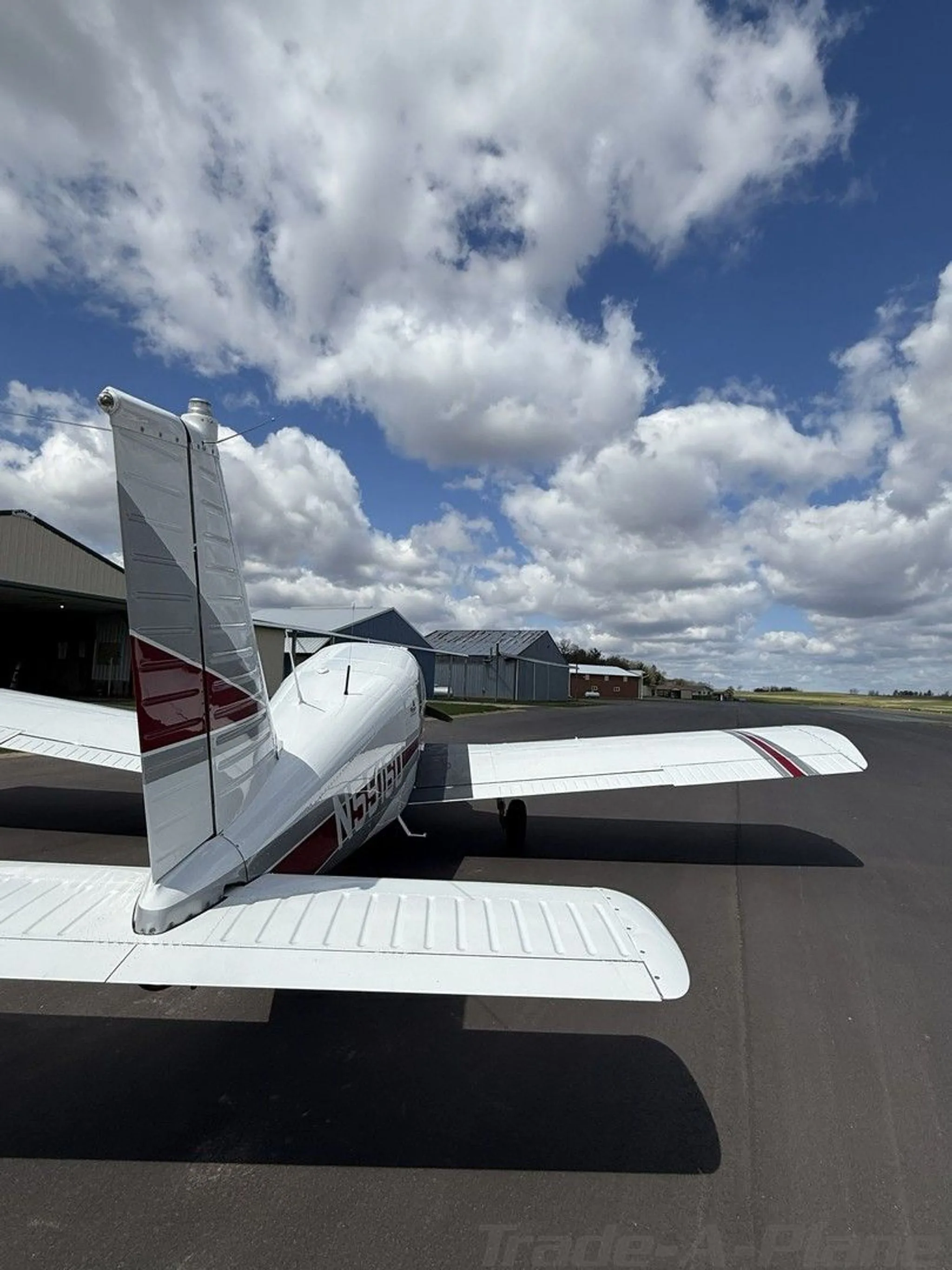 A close-up rear view of the tail and right wing of a white Piper Cherokee aircraft.