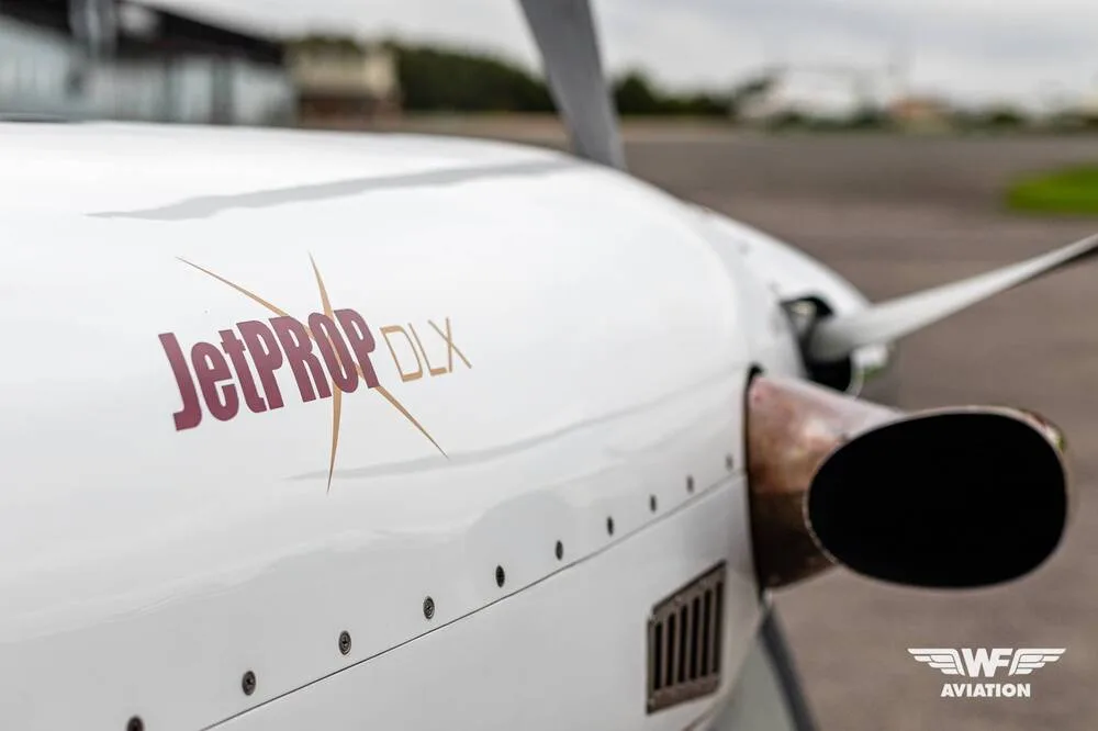 A close-up of the aircraft's white nose, showing the "JetPROP DLX" logo and the engine exhaust pipe.