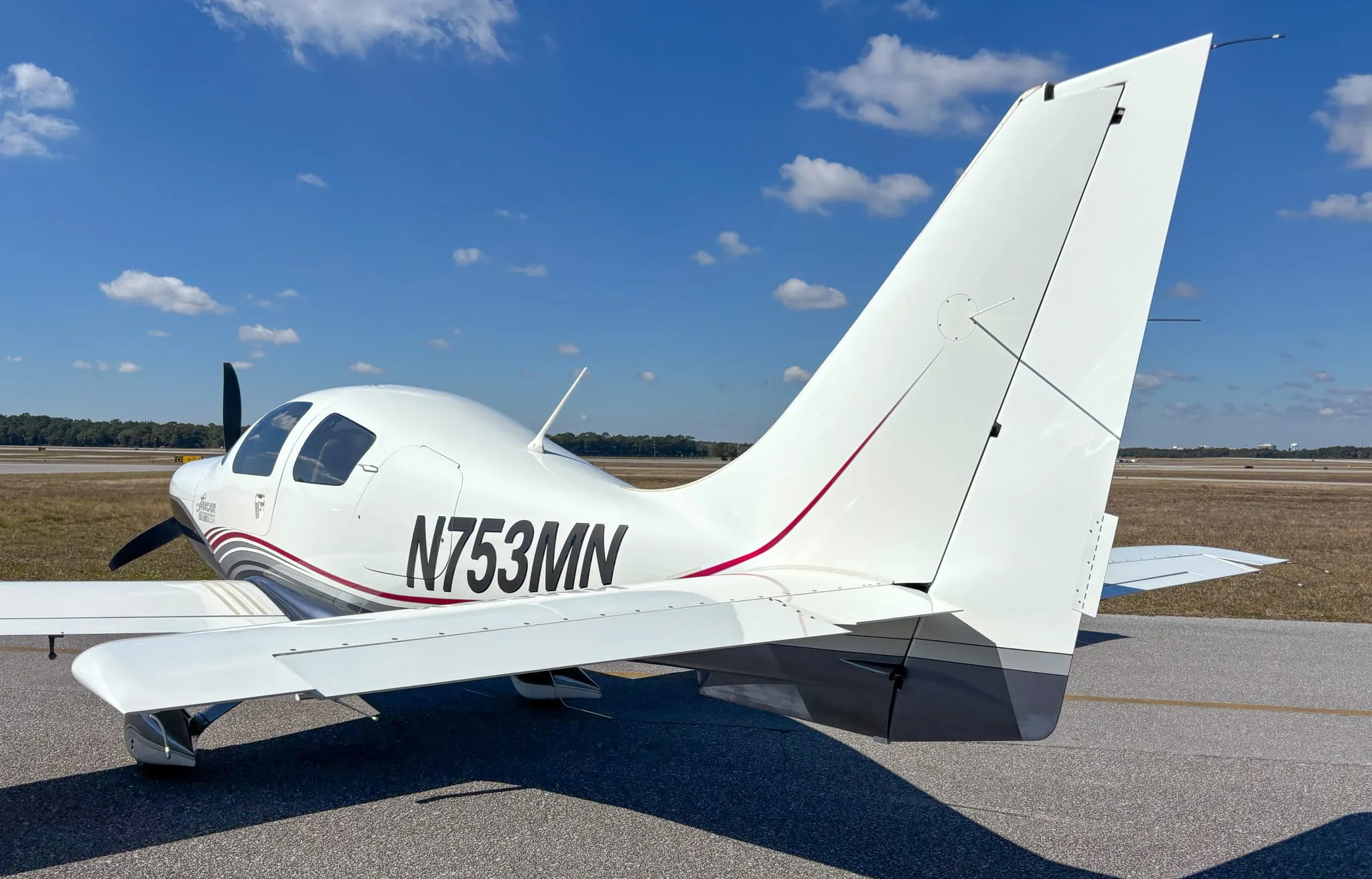 Rear-quarter view of the Lancair Columbia 400 N753MN on a sunny day at the airport.