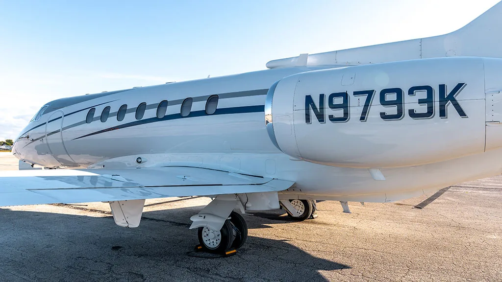 A close-up view of the mid-fuselage and engine of the white business jet N9793K, showing the tail number.