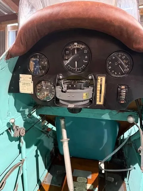 A detailed view of the vintage aircraft's instrument panel, showing a compass and various dials.
