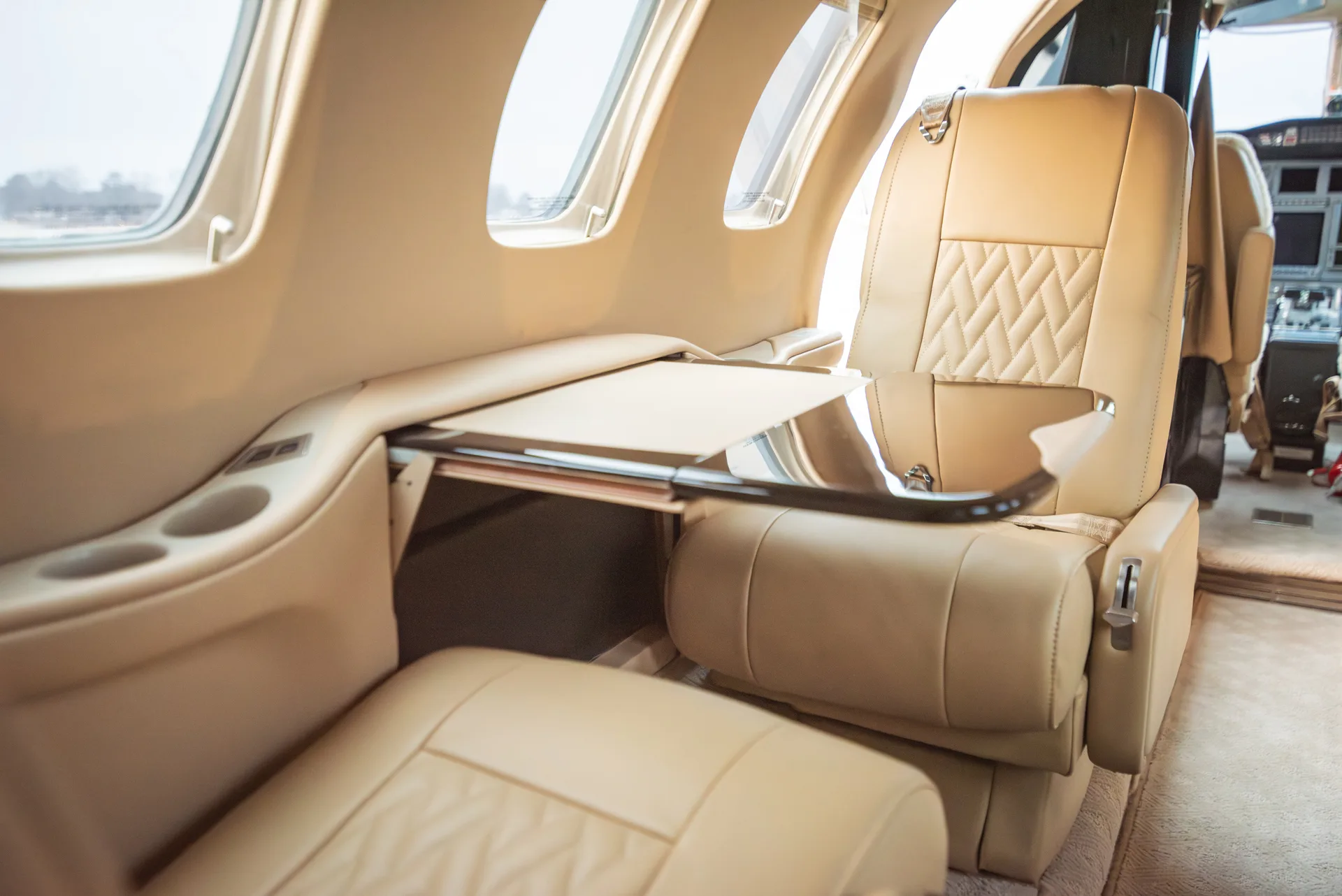 A Citation Bravo cabin seat with a fold-out table and cup holders.