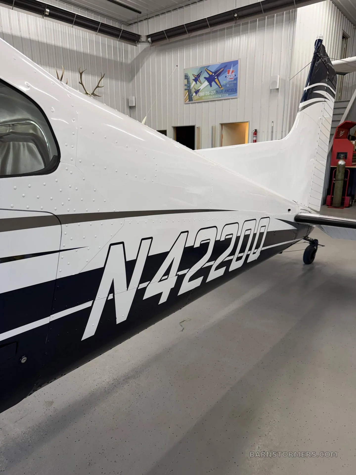 A close-up view of the white and blue fuselage of an aircraft with tail number N42200, parked in a hangar.