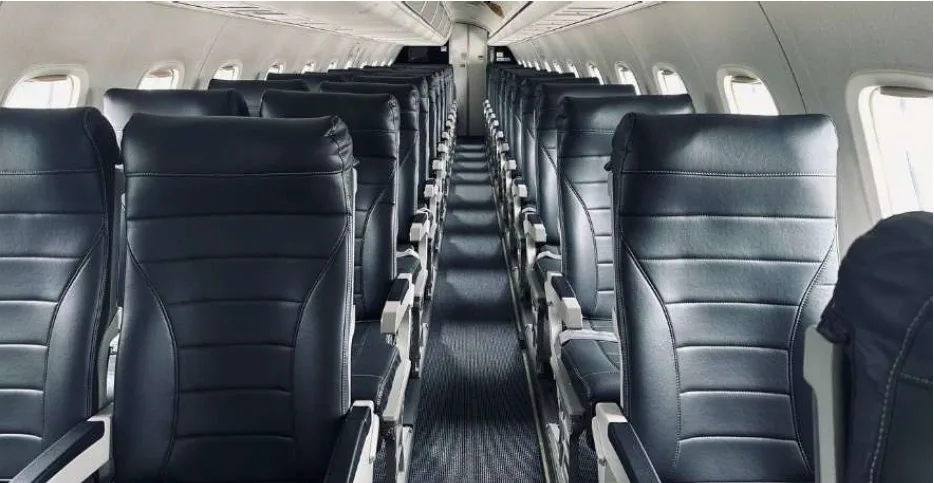 An interior view of an aircraft cabin with rows of dark grey passenger seats.