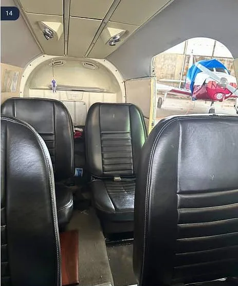 The interior cabin of a Piper Seneca I aircraft, showing black leather seats.