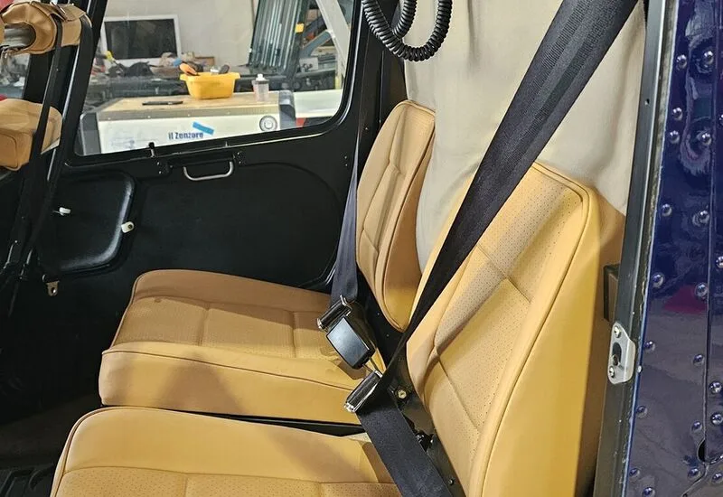 Close-up of the tan leather seats and seatbelts inside the helicopter cabin.