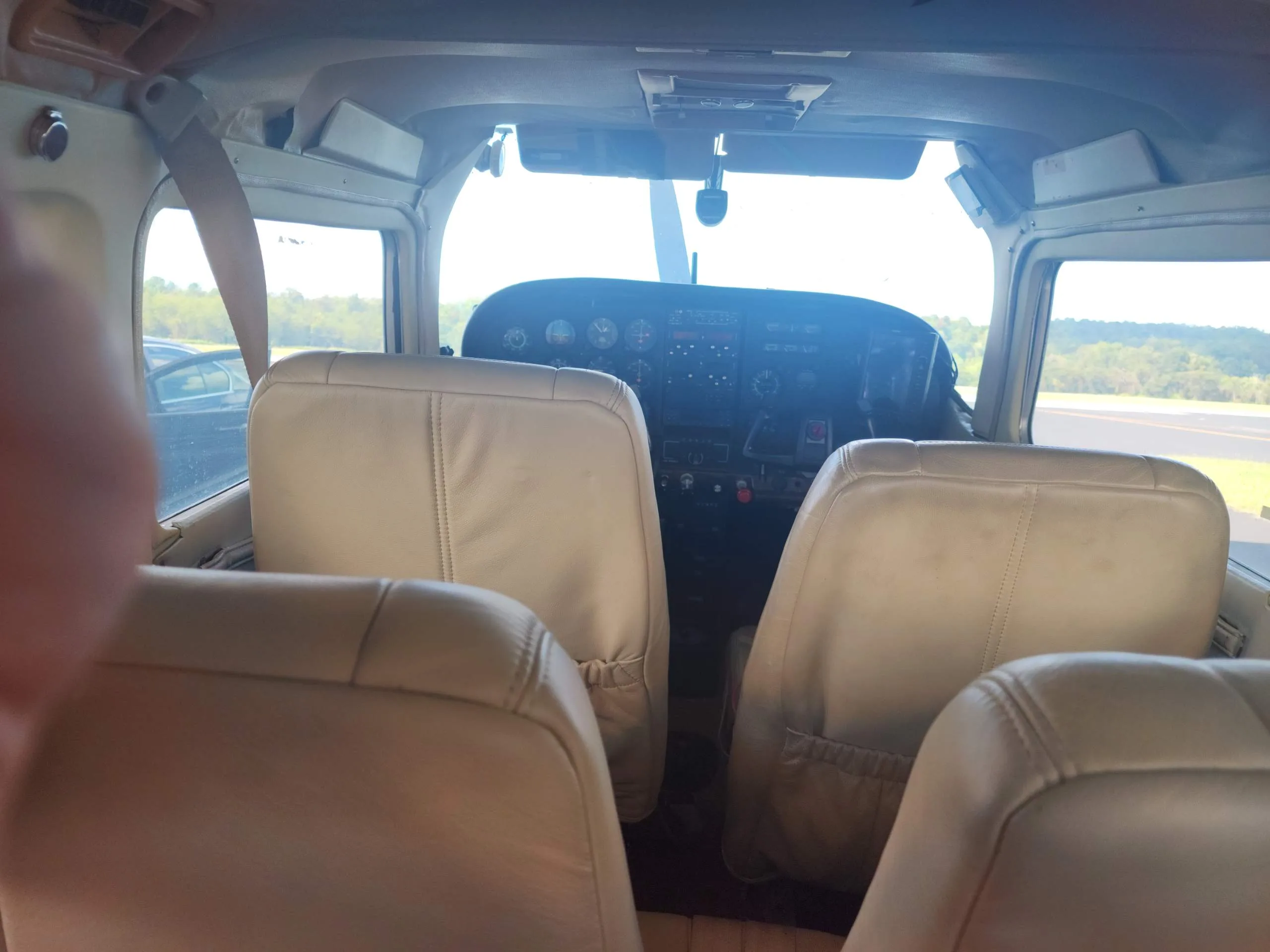 View from the rear seats of a light brown aircraft interior looking towards the cockpit.