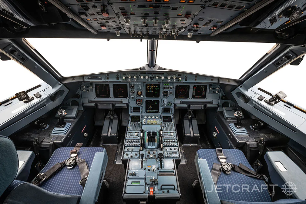 The cockpit of an Airbus A320 family aircraft with a clear view of the instrument panel and controls.