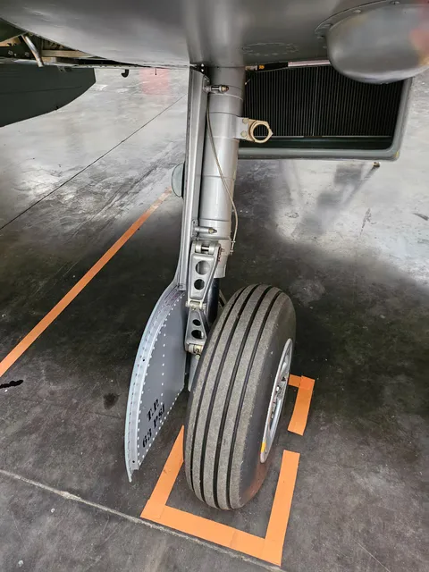 A close-up view of the main landing gear and wheel of a Supermarine Spitfire on a hangar floor.
