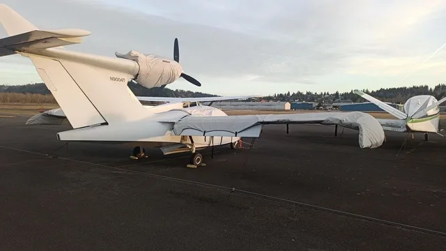 The white Searey amphibian aircraft, N9004T, is parked on an airfield with covers on its propeller and wings.