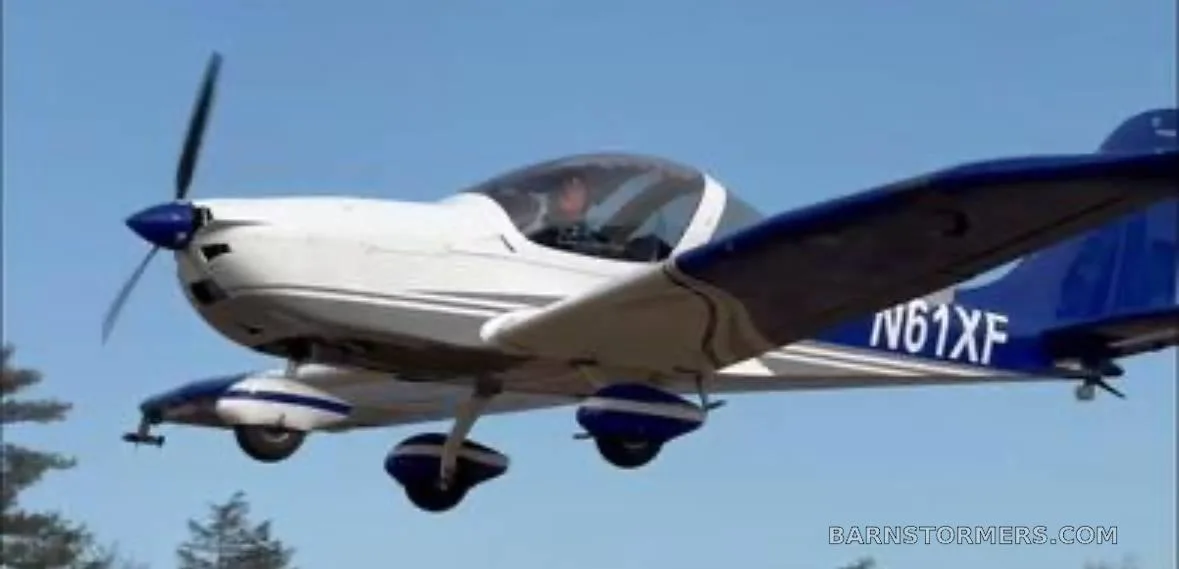 A white and blue Evektor Harmony Light Sport aircraft (N61XF) is shown in flight against a clear blue sky.
