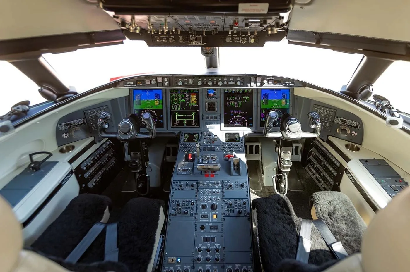The cockpit of a modern business jet, featuring multiple digital displays and a complex control panel.