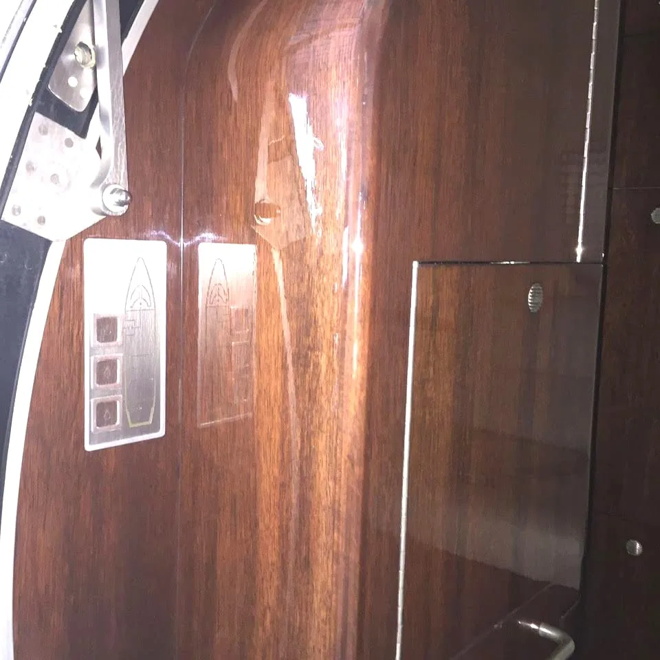 A close-up of a glossy dark wood paneling with silver controls inside an aircraft.
