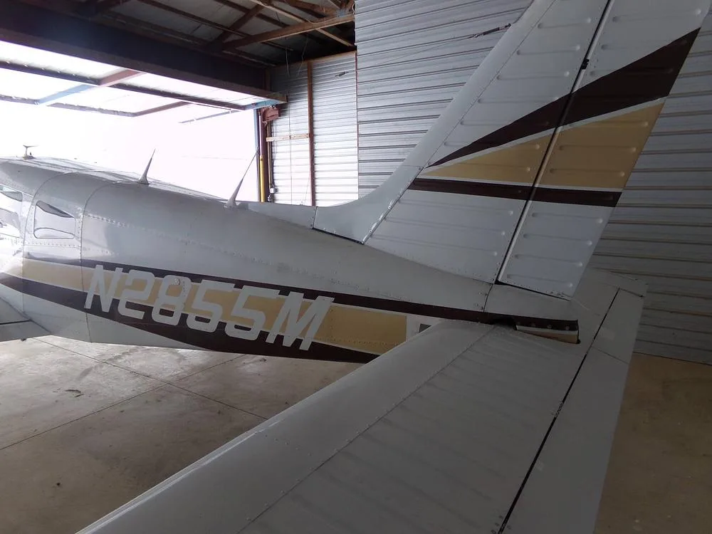 A close-up view of the tail and rear fuselage of a white aircraft with brown and gold stripes, clearly showing the registration N2855M.