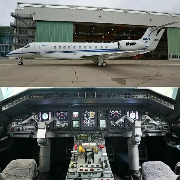 A white Embraer Legacy business jet with blue stripes parked on a tarmac in front of a hangar, with a view of its detailed cockpit instrument panel below.