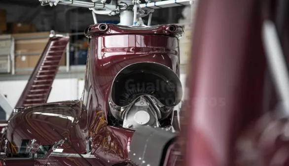 A close-up view of the engine intake and upper fuselage of a burgundy helicopter.