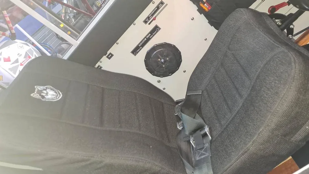 The black fabric pilot's seat with a Husky logo on the headrest, inside the aircraft cabin.