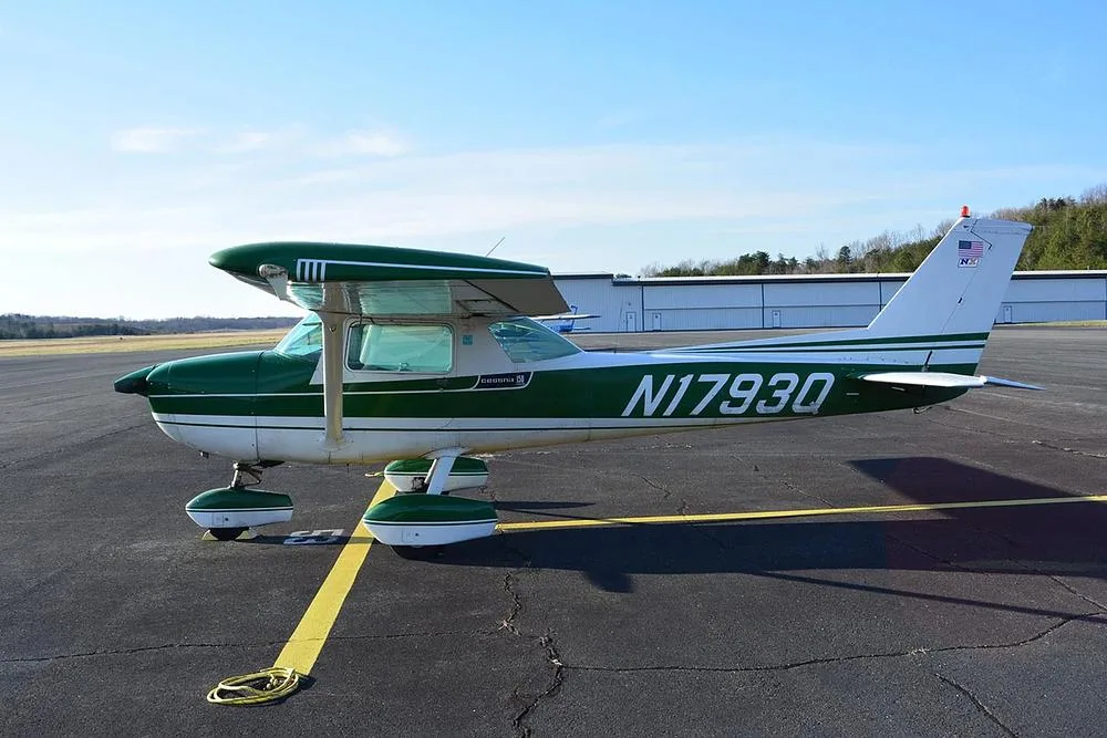 A green and white Cessna 172 aircraft, registration N1793Q, parked on an airport tarmac with hangars in the background.