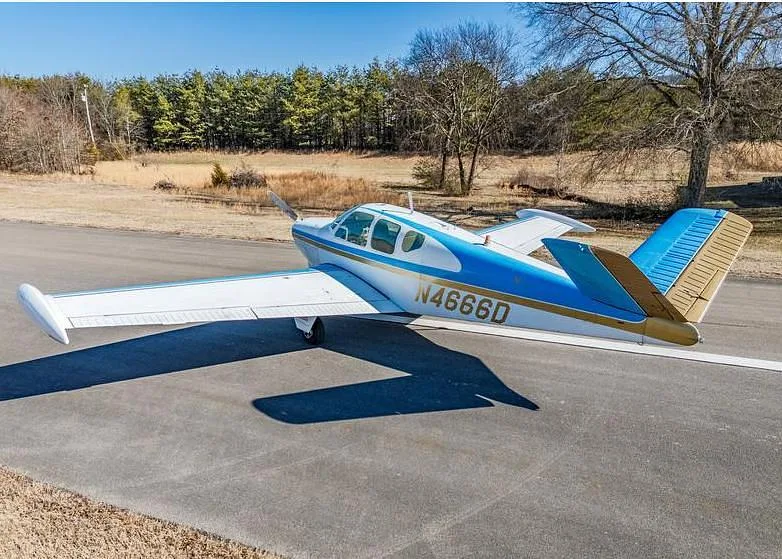 A side-rear view of the white and blue single-engine aircraft N4666D on an asphalt runway.