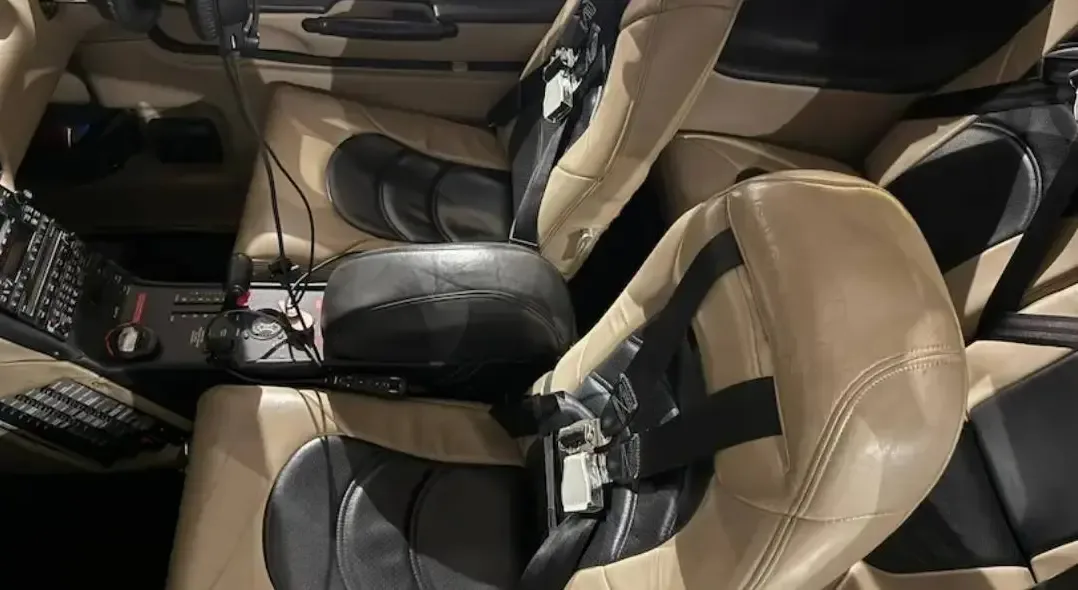 The front two seats of the aircraft, upholstered in tan and black leather, with a view of the center console.