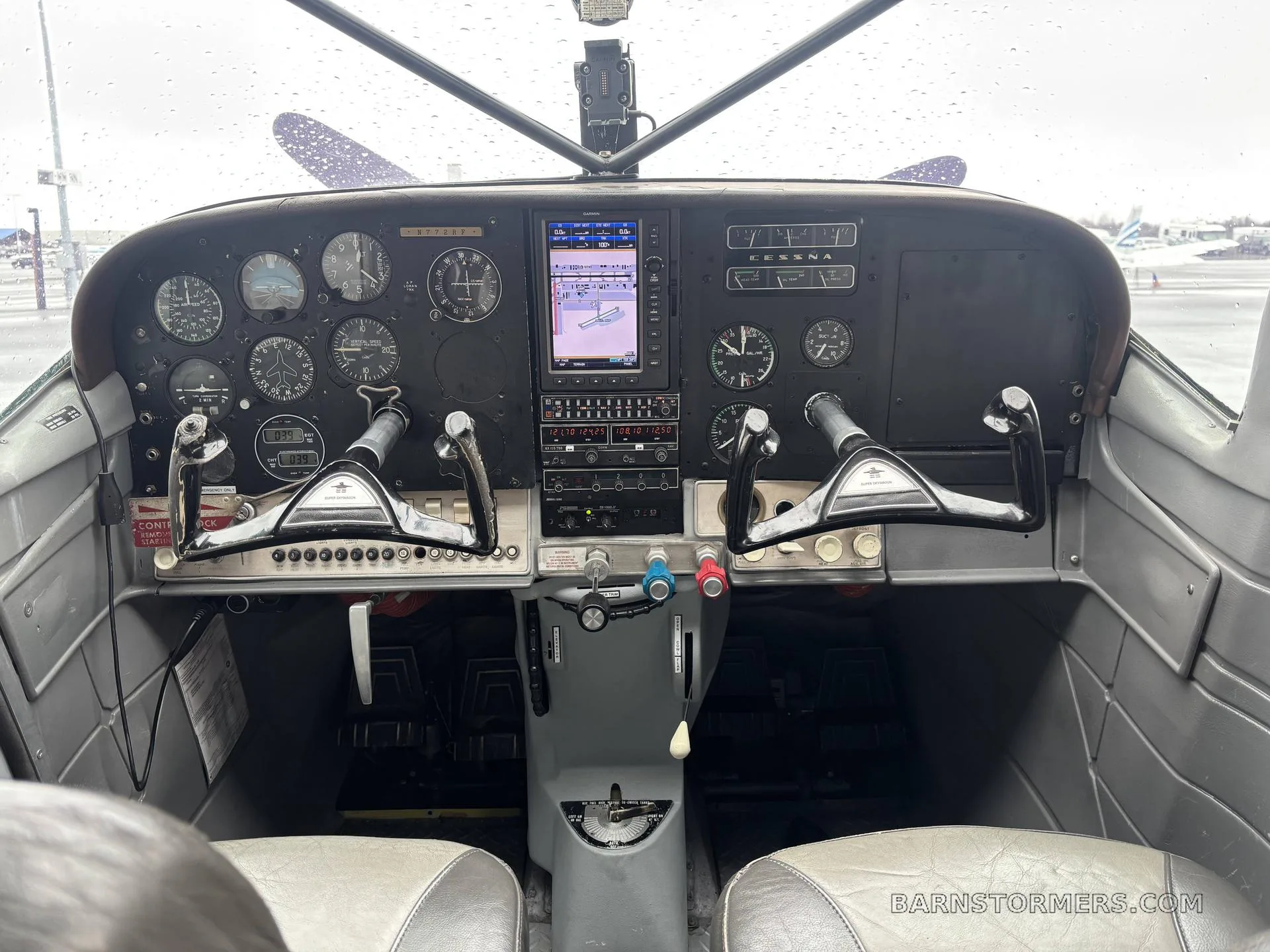 The cockpit of a small aircraft with a mix of analog gauges and a modern digital display, seen from the pilot's seat.