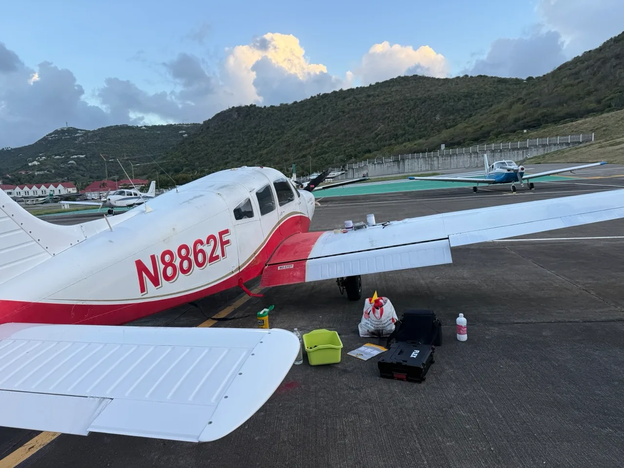 A close-up view of the right wing and tail of the white and red Piper Cherokee Warrior (N8862F) on an airfield.