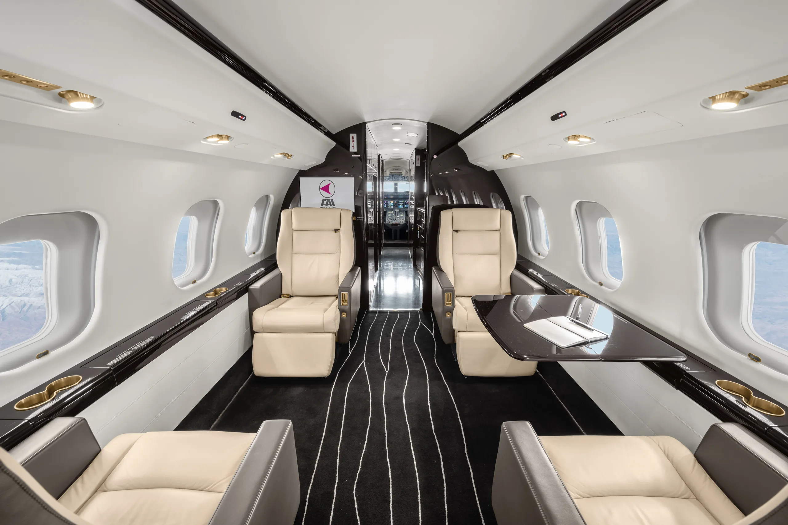 A luxurious aircraft cabin interior with cream leather seats, dark wood accents, and a black and white striped carpet.