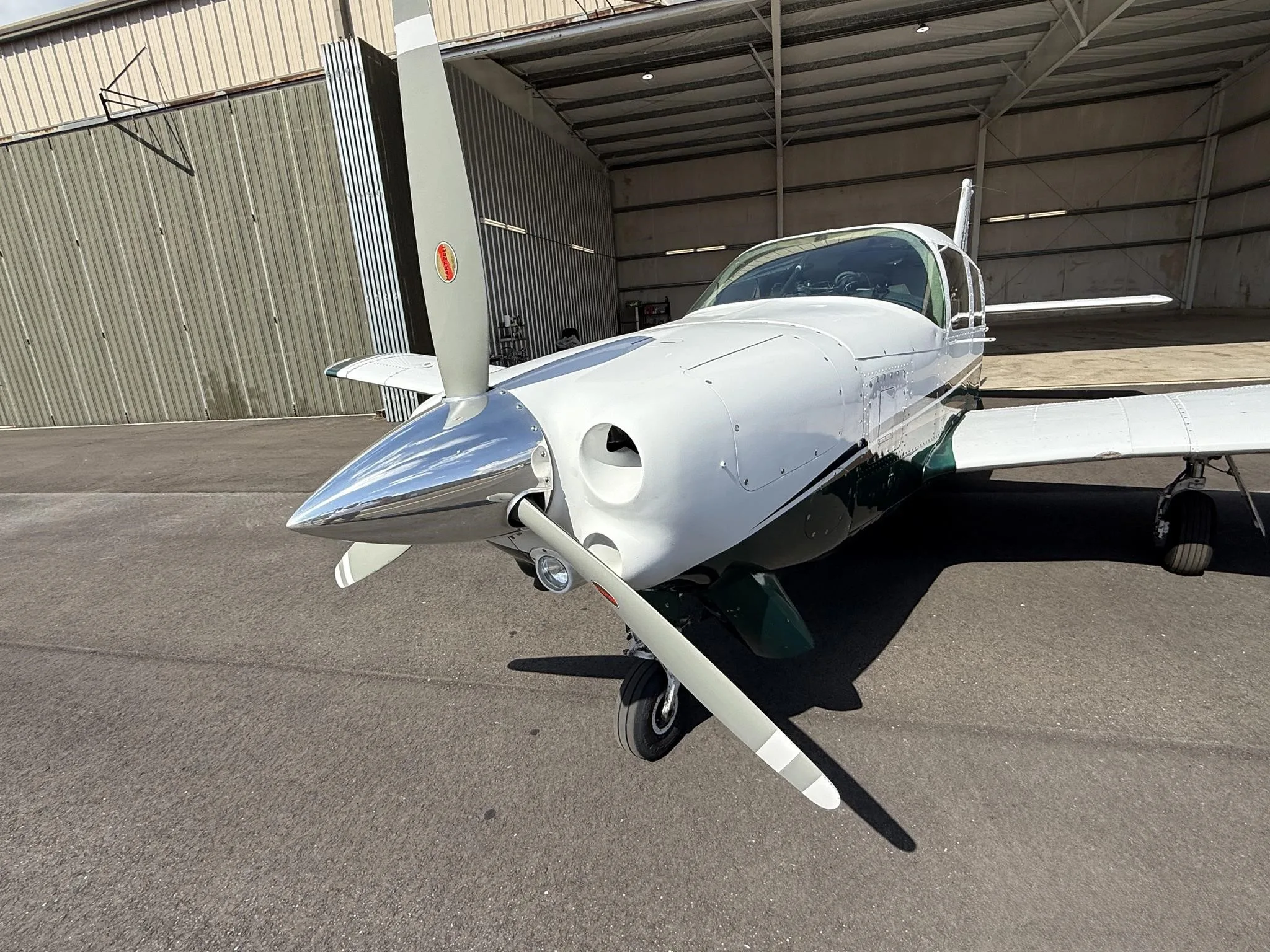 A close-up front view of the propeller and nose of the white and green Piper PA-32R-300 Cherokee Lance II.